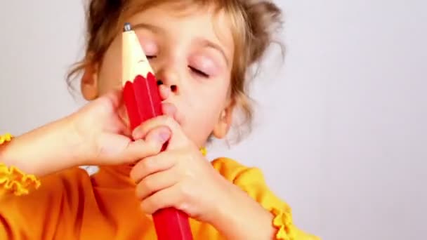 Маленькая девочка держит большой карандаш и улыбается — стоковое видео