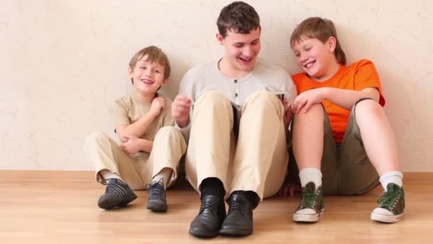 Tři chlapci sedět na podlaze a četl časopis — Stock video