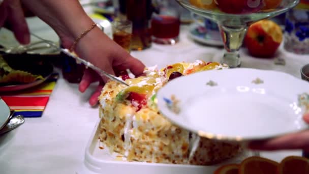 Hände schneiden süßen Obstkuchen mit Messer ab und legen Stück auf Teller — Stockvideo