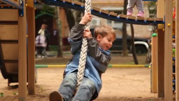 Rapaz balançar na corda no parque infantil — Vídeo de Stock