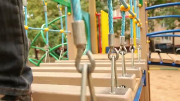 Menina e menino caminham em degraus pendurados no playground — Vídeo de Stock