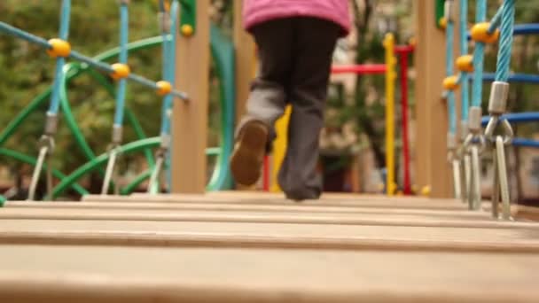 Маленькая девочка бежит вниз по деревянным ступенькам несколько раз на детской площадке — стоковое видео