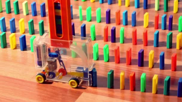 Man turn on toy machine wich begin moves and put domino blocks — Stock Video