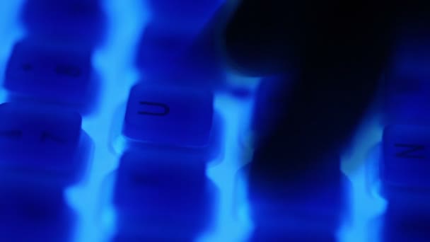 Fingers push buttons of keyboard with blue backlight in dark — Stock Video