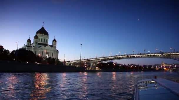 Schiff schippert den Fluss hinunter, Christ-Erlöser-Kathedrale und patriarchalische Brücke am Abend — Stockvideo