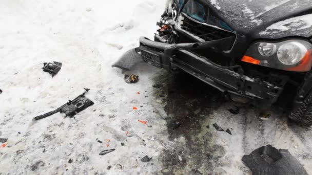 Сильно потрепанный автомобиль на ледяной дороге с мигающими аварийными фонарями и вокруг обломков — стоковое видео