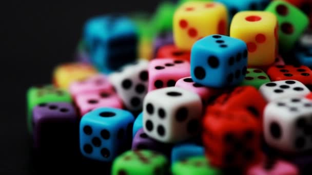 Many colorful dice stacked in pile rotate on black — Stock Video