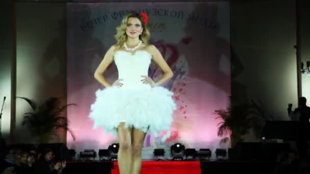 Model in short white wedding dress with skirt of feathers from French couturier walks catwalk — Stok video