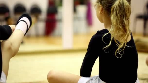 Kis lány ül a padló és a központjáig terjed emelkedett a láb — Stock videók