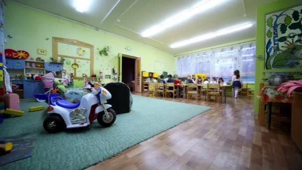 Varios niños, niños y niñas, se sientan a la mesa en el jardín de infantes — Vídeo de stock