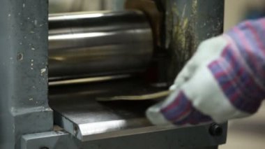 Adam defalarca metal bir plaka haddeleme makine içinde ekler.