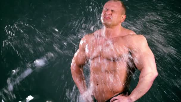 Bodybuilder stand, poi l'acqua spruzzata su di lui da fuori dello schermo — Video Stock