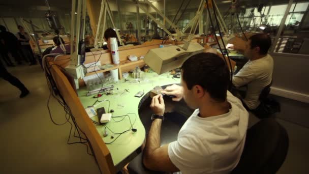 Мужчины работают за столиками в ювелирной мастерской на производстве ювелирного дома Estet — стоковое видео