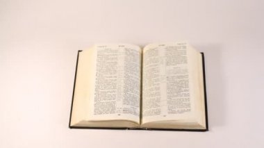 İncil (uncopyrighted kitap) beyaz masaya yatıyor, sayfaları Rüzgar tarafından aranır