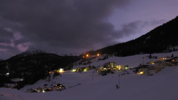 Snöplog går nära hotell i dalen på natten — Stockvideo