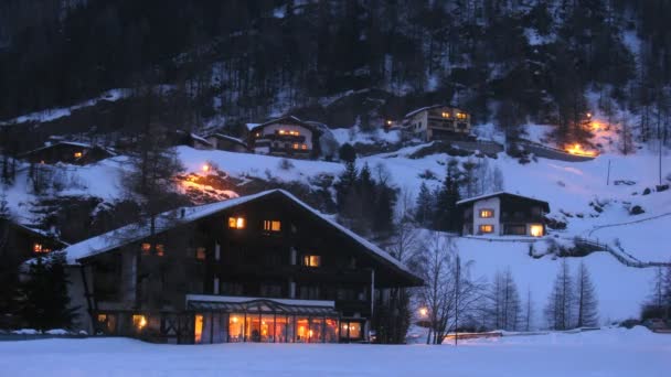 Windows centrálního lázeňského hotelu jsou zářilo do večerní světlo, které se odráží od sněhu — Stock video
