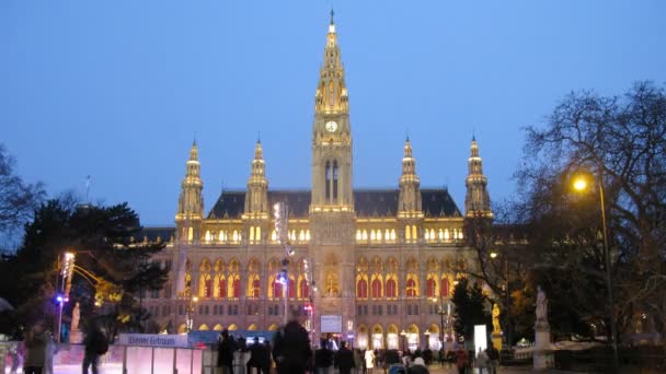 La gente va a conducir en la pista de patinaje frente a Rathaus por la noche — Vídeo de stock