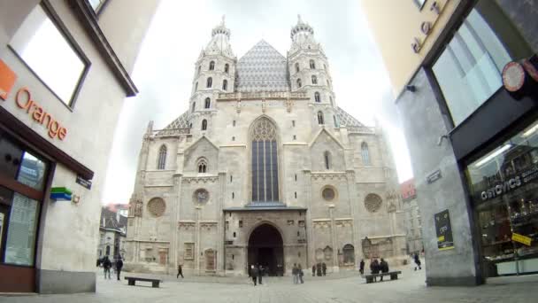 Turistas caminham em frente à igreja Stephansdom entre dois edifícios modernos — Vídeo de Stock