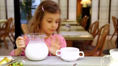 küçük kız süt kabı alır ve plaka restoran dökülen