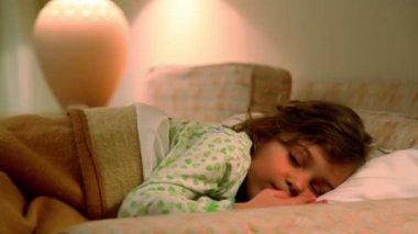 küçük kız yatakta yatıyor ve gözleri lambası arka plan losyonları