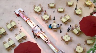 People walk and sit at tables in café