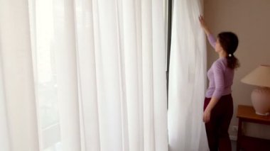 genç kadın perdeleri çizer ve şehir dışında sokak penceresi açılır