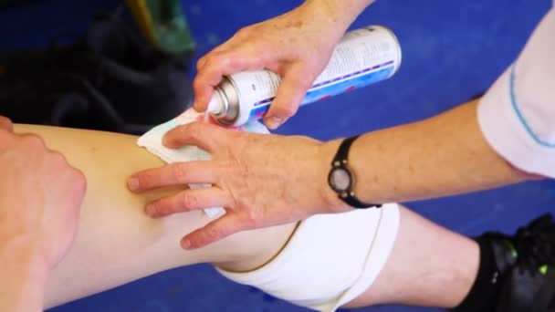 Sports doctor does analgesic spray on knee of sportsman after trauma in basketball — Stock Video