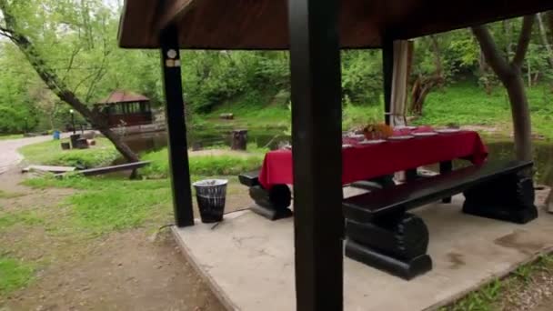 Table is set in summerhouses ashore of small pond at among trees at summer — Stock Video