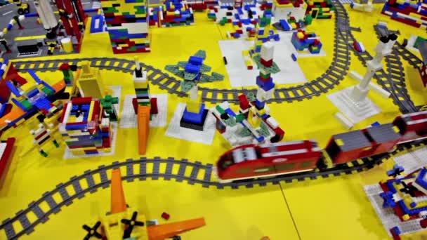 Toy train moves by railroad among different objects — Stock Video