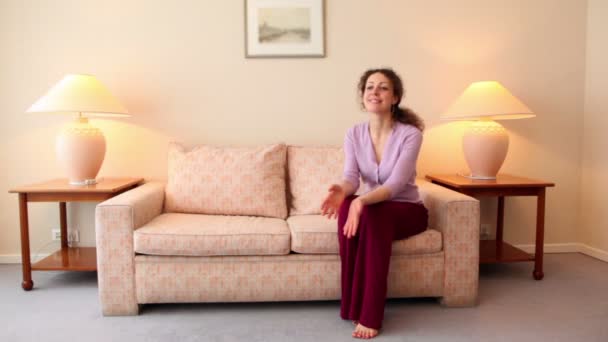 Little girl runs to her mother sit on sofa at room with lamp on each side — Stock Video