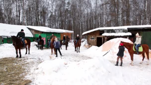 Varias personas se sientan a caballo en el patio estable — Vídeos de Stock