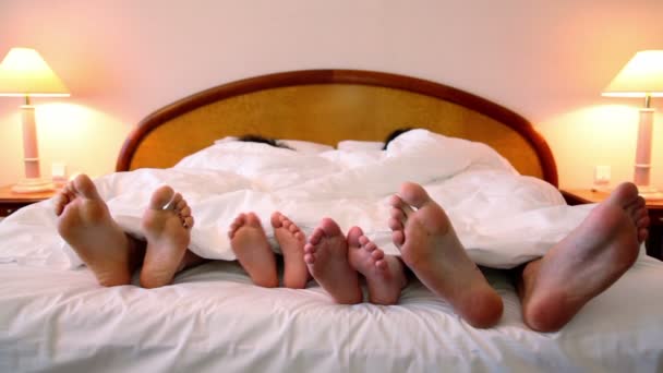 Rodina ležela v posteli pod dekou a pohybovat bez bot nohy — Stock video
