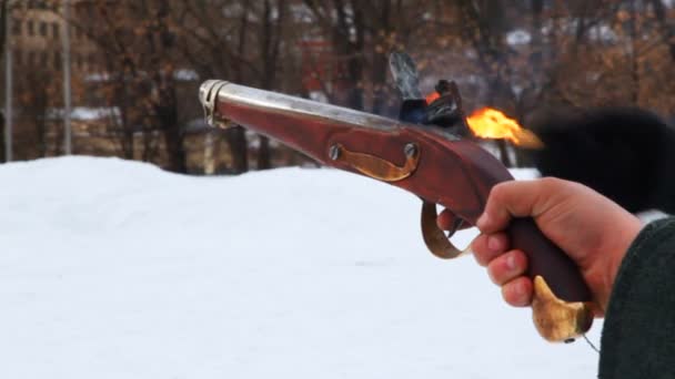 Hand of one man holds ancient pistol, and other lights fuse — Stock Video