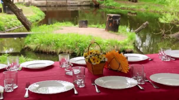 Tavolo da pranzo è impostato in pergola a riva di piccolo stagno tra gli alberi in estate — Video Stock