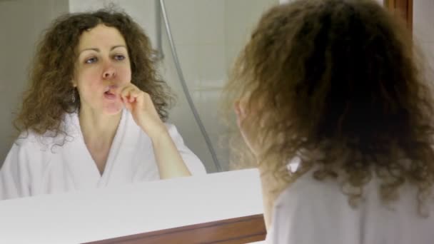 Nő rajta fehér fürdőköpeny kefe fogak tükör előtt — Stock videók