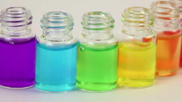 Six bouteilles transparentes ouvertes se déplace latéralement avec de l'huile de couleur sur eux 