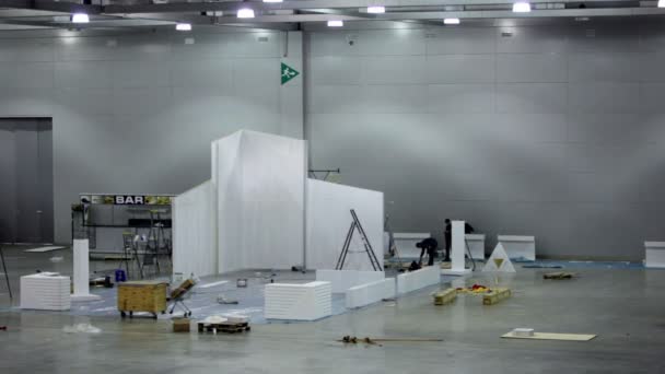 Peu de travailleurs construisent stand d'exposition, tour de machine de nettoyage — Video