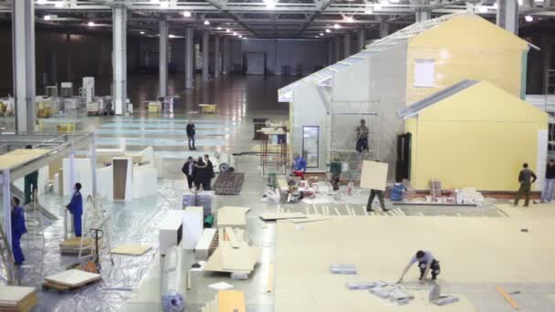 Builders work on construction site in exhibition hangar — Stock Video