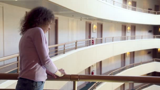 Mujer de pie en el balcón con pasamanos en el edificio de piso múltiple — Vídeos de Stock