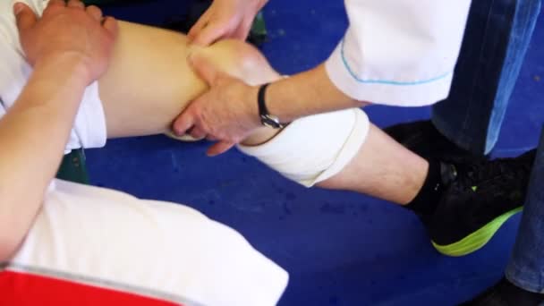 Sports doctor does massage patella of sportsman after trauma in basketball — Stock Video