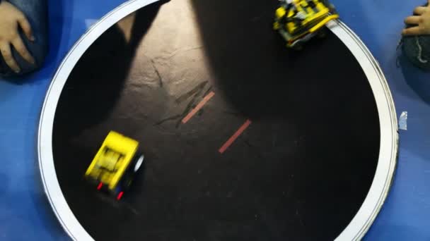 Twee robot speelgoedauto's concurreren op ronde platform, duwt een andere buiten — Stockvideo