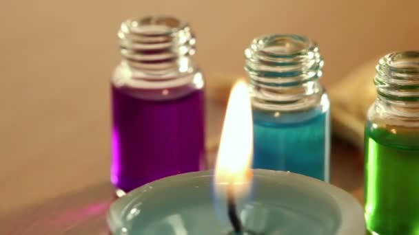 Two candles burn, few open bottles with color aroma oil and sea star lay — Stock Video