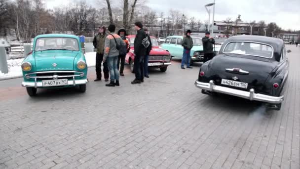 Несколько человек стоят возле старых автомобилей в парке на открытии ретро-сезона — стоковое видео