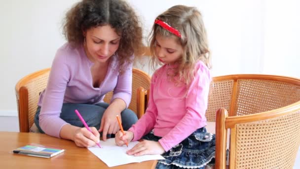 Madre con su hija sentarse en sillas en la mesa de madera y dibujar con marcadores — Vídeos de Stock