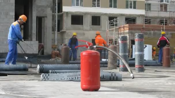 Extinguisher stands in front of workers which work with fire on housing estate Losinyj Island — Stock Video