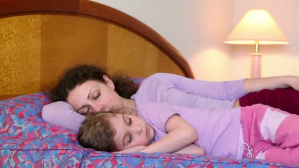 Мать и дочь лежали на кровати, мама спит, но девушка не — стоковое видео