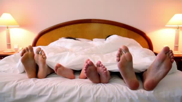 Famiglia giaceva nel letto sotto coperta e spostare i piedi bootless — Video Stock