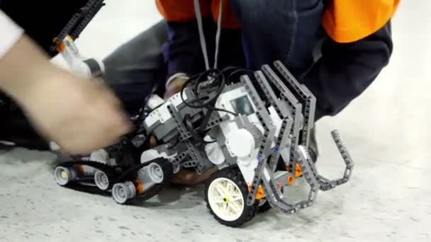 Le persone operano con robot giocattolo sul pavimento — Video Stock