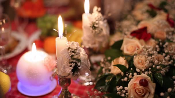 In de schemering op feestelijke tafel zijn er kaarsen, boeketten, glazen — Stockvideo