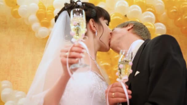 La pareja recién casada besa las copas de champán en las manos contra la pared — Vídeos de Stock